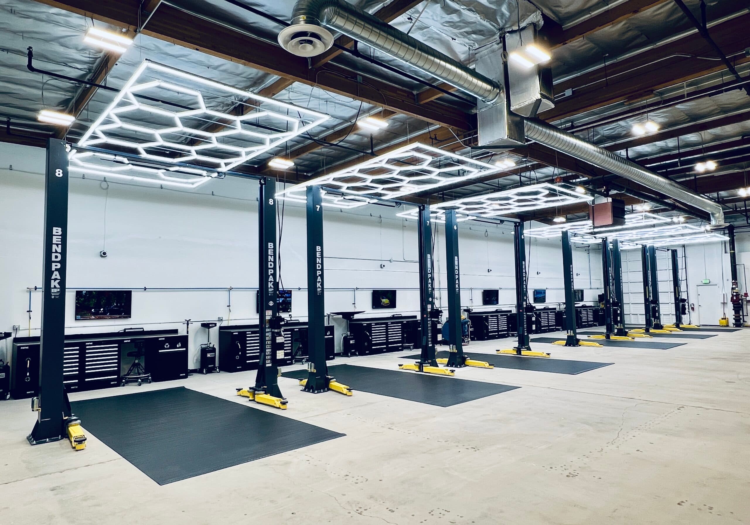 Row of clean, professional two-post vehicle hoist bays inside the Apex DIY Melbourne workshop